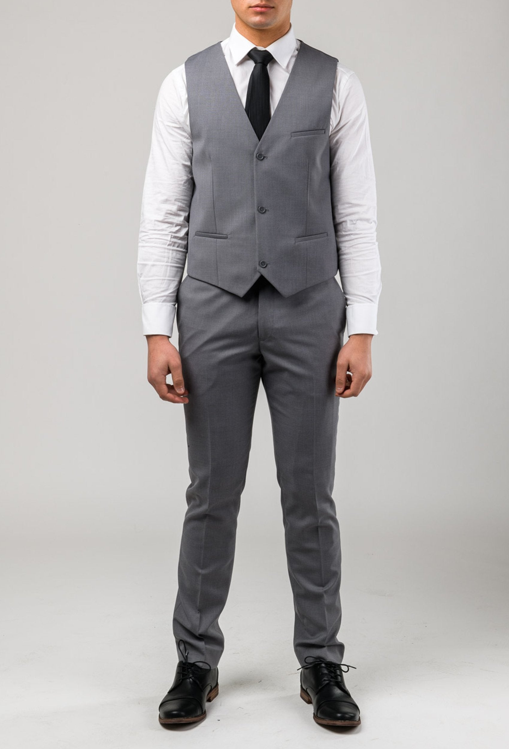 a grey vest and trouser by aston man worn over a white shirt with a black long tie. The model stands facing thhe front with his arms down at his side, his face is cut out of the picture