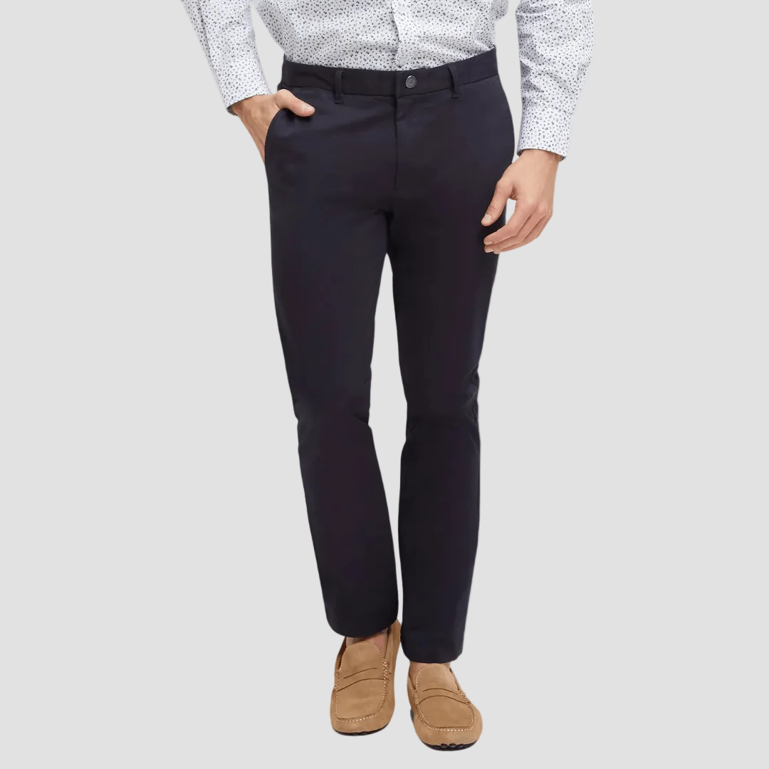 A man wearing navy blue chino trousers with a regular fit, featuring a zip fly, button closure, and side and back pockets. He is also wearing a patterned shirt and tan shoes.
