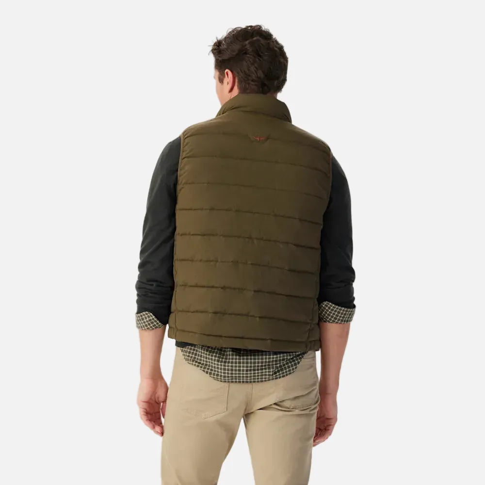 Man wearing a green vest over a dark shirt with a beige background