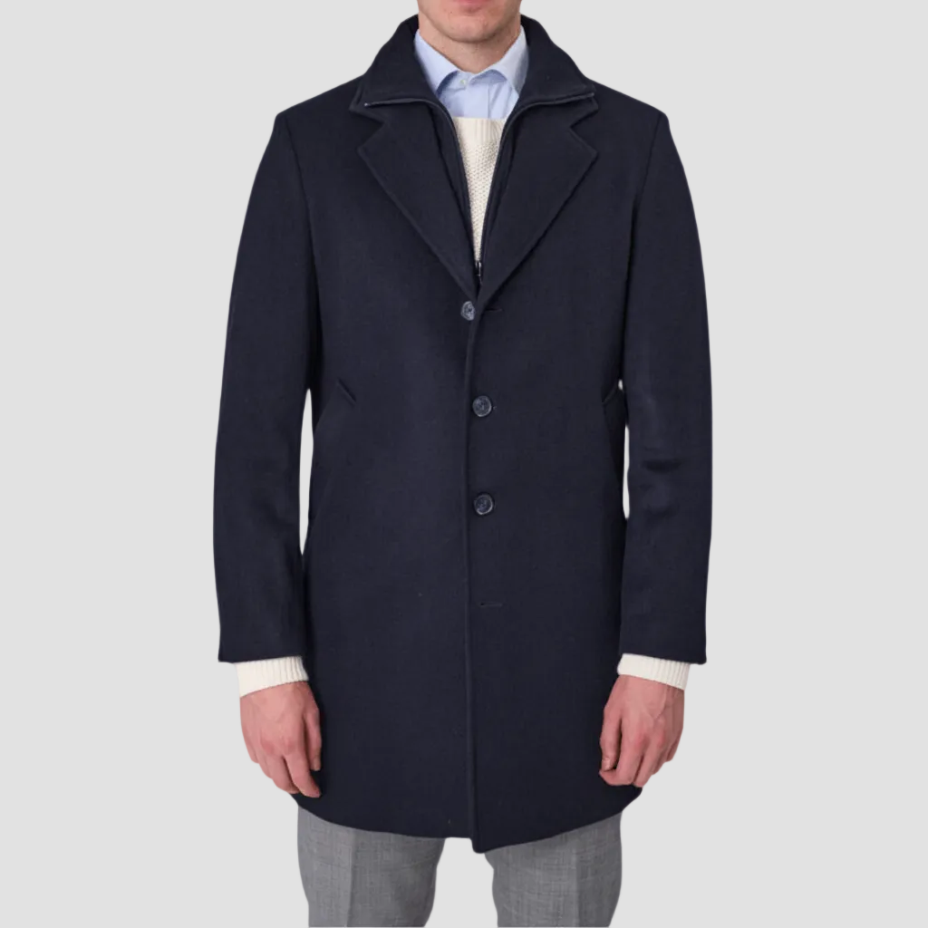 A navy blue, single-breasted, four-button front Savile Row coat with a removable collar, pictured on a male model.