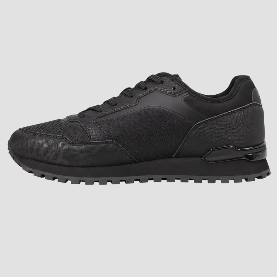 A black low-top athletic sneaker with a textured mesh and synthetic upper, black laces, and a chunky black sole, shown from a side profile view on a white background.