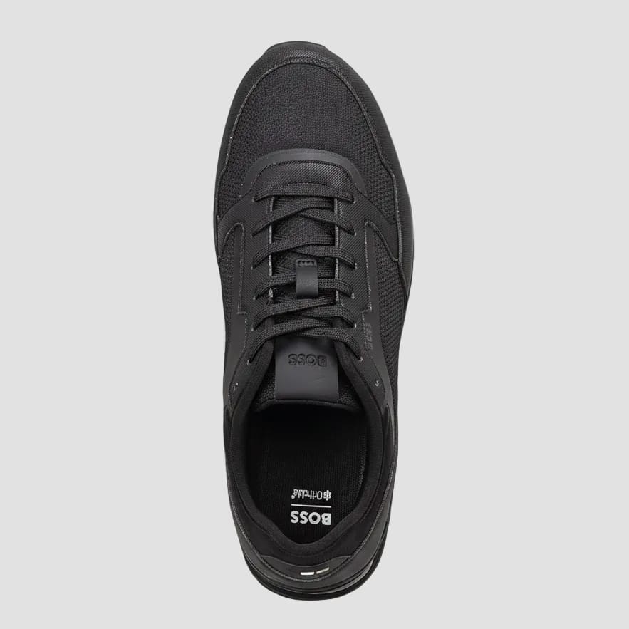 A top-down view of a black BOSS low-top sneaker, showing the mesh upper, black laces, and the BOSS branding on the tongue and insole.