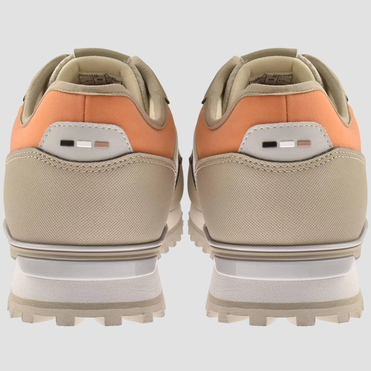 A pair of low-top sneakers shown from the back, featuring a beige canvas base, a peach-orange leather collar, and a chunky white and beige sole.