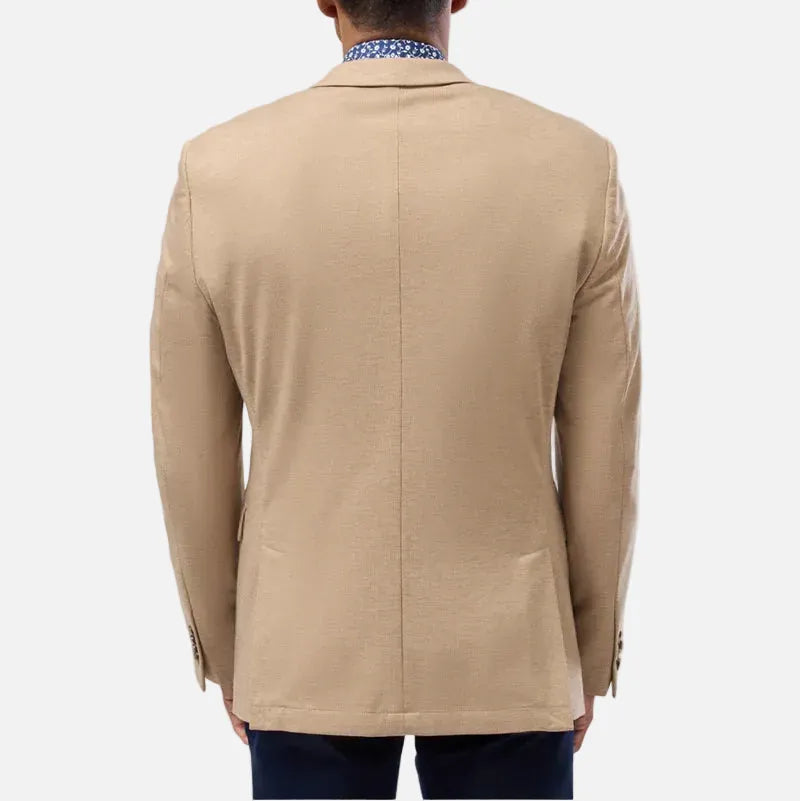 A man viewed from the back wearing a beige blazer over a patterned blue and white collared shirt, set against a plain light gray background.