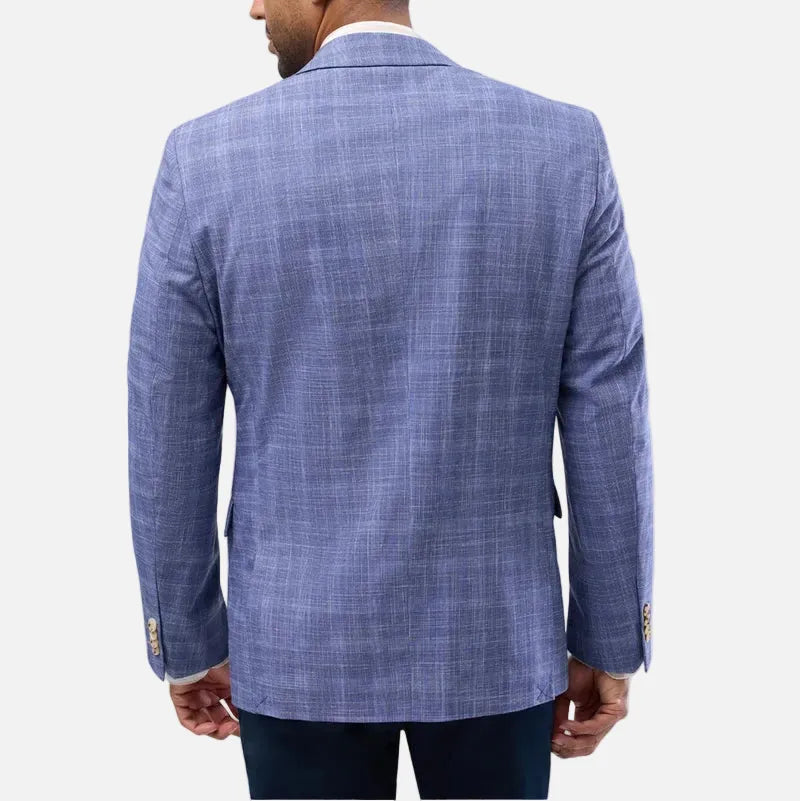 A man viewed from the back wearing a blue textured blazer with a subtle plaid pattern, paired with dark trousers, against a light gray studio background.