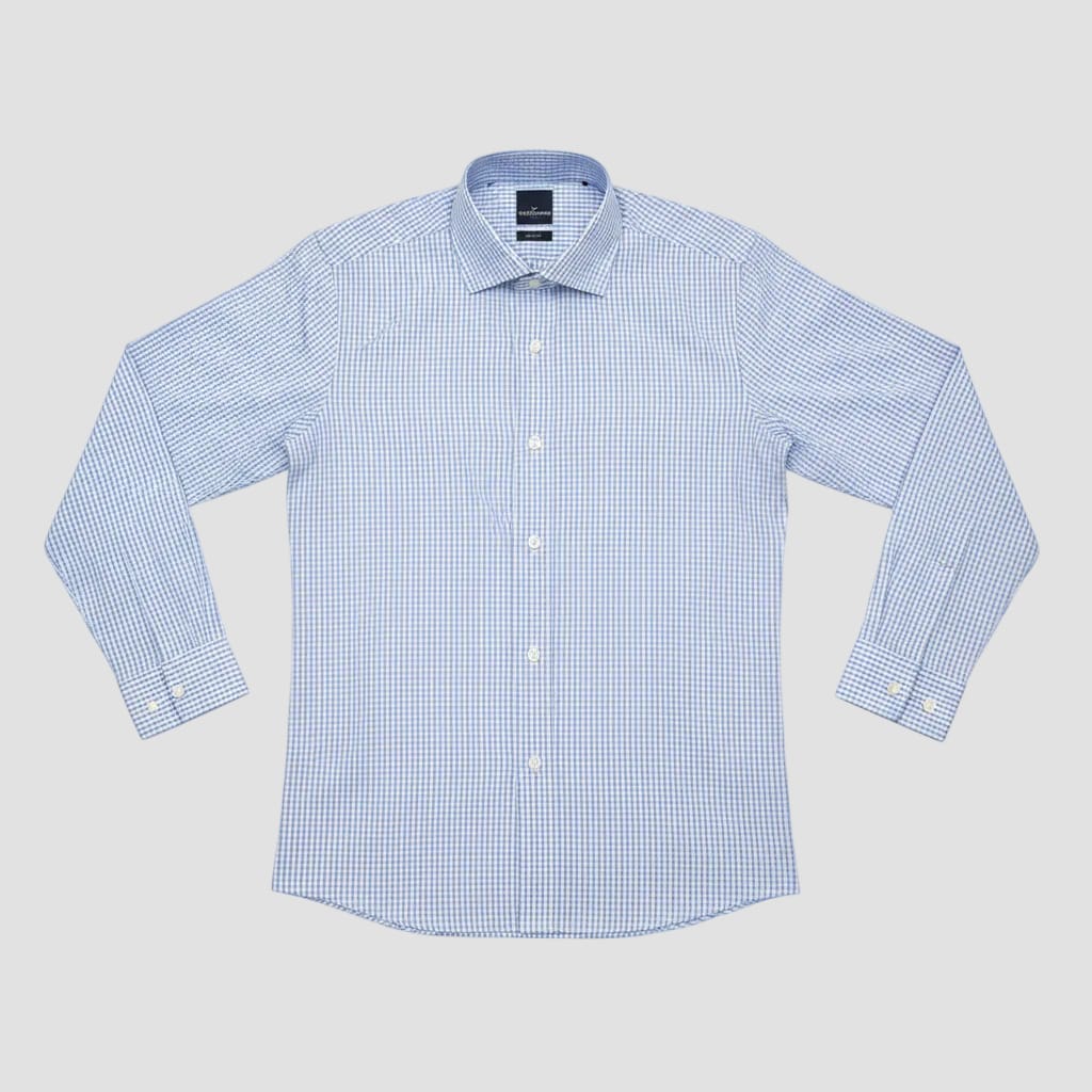 Folded blue checkered shirt in clear plastic packaging on a pink surface.