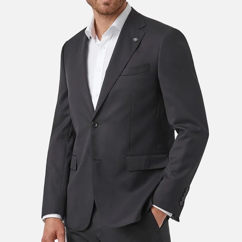 A man wearing a black suit jacket and matching trousers over a white dress shirt, photographed against a plain white background.