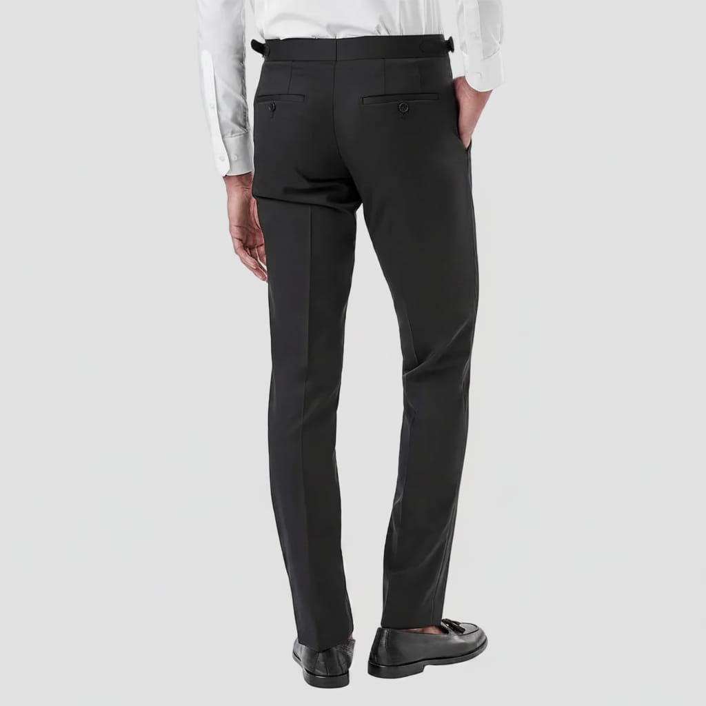 Rear view of a man wearing black dress pants with a white dress shirt and black loafers, shown against a plain white studio background.