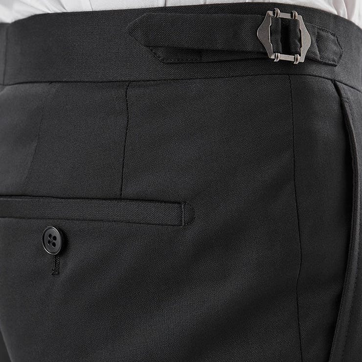 Close-up of a person wearing black tailored trousers with a matching black belt featuring a silver buckle, paired with a white shirt.