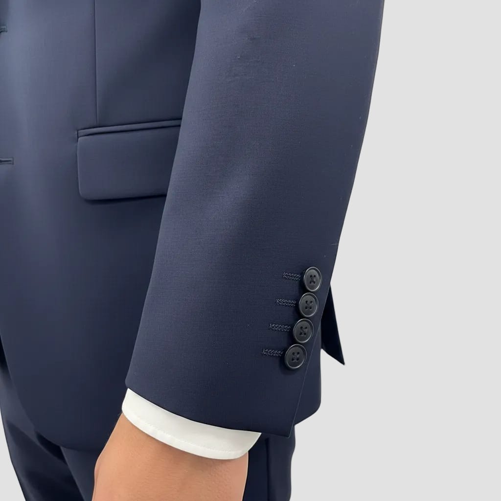 Navy blue suit jacket with white shirt cuff on a light gray background