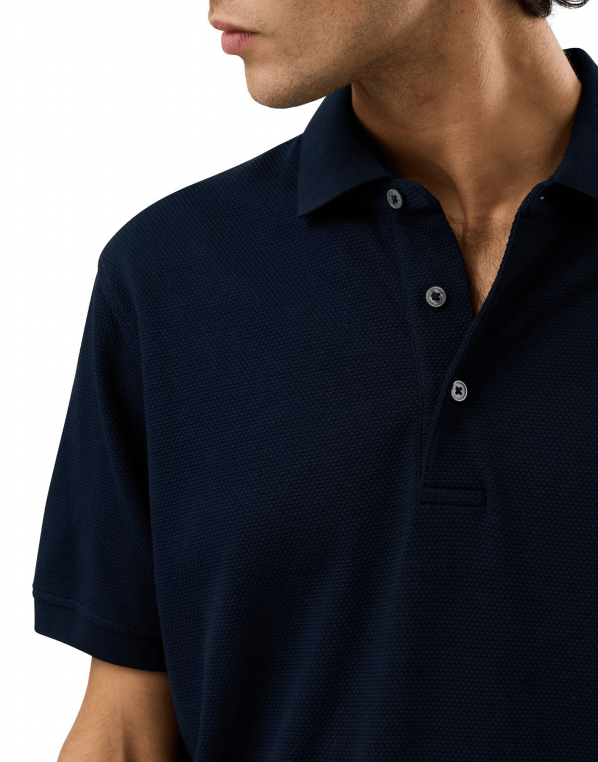 Close-up of a man wearing a dark navy blue short-sleeve polo shirt with a textured knit fabric and silver buttons.