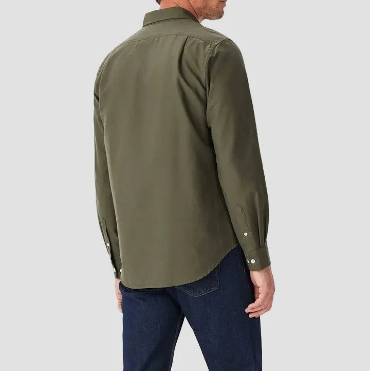 Man wearing an olive green shirt and blue jeans on a white background