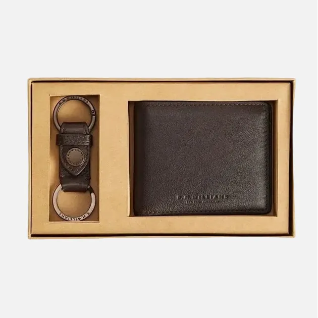 A dark brown leather bifold wallet and matching leather keychain presented in a gold-colored gift box on a white background.