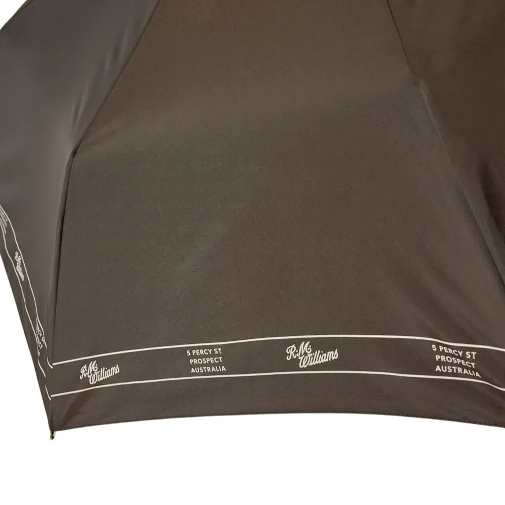 Close-up of a brown umbrella with 'R.M. Williams' branding on a white background