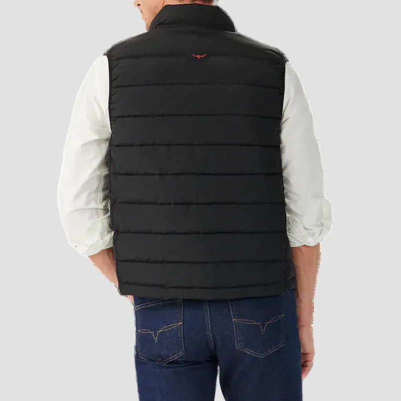 Man wearing a black puffer vest over a white shirt on a white background