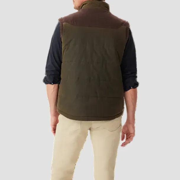 Man wearing a brown vest over a dark shirt with beige pants on a white background