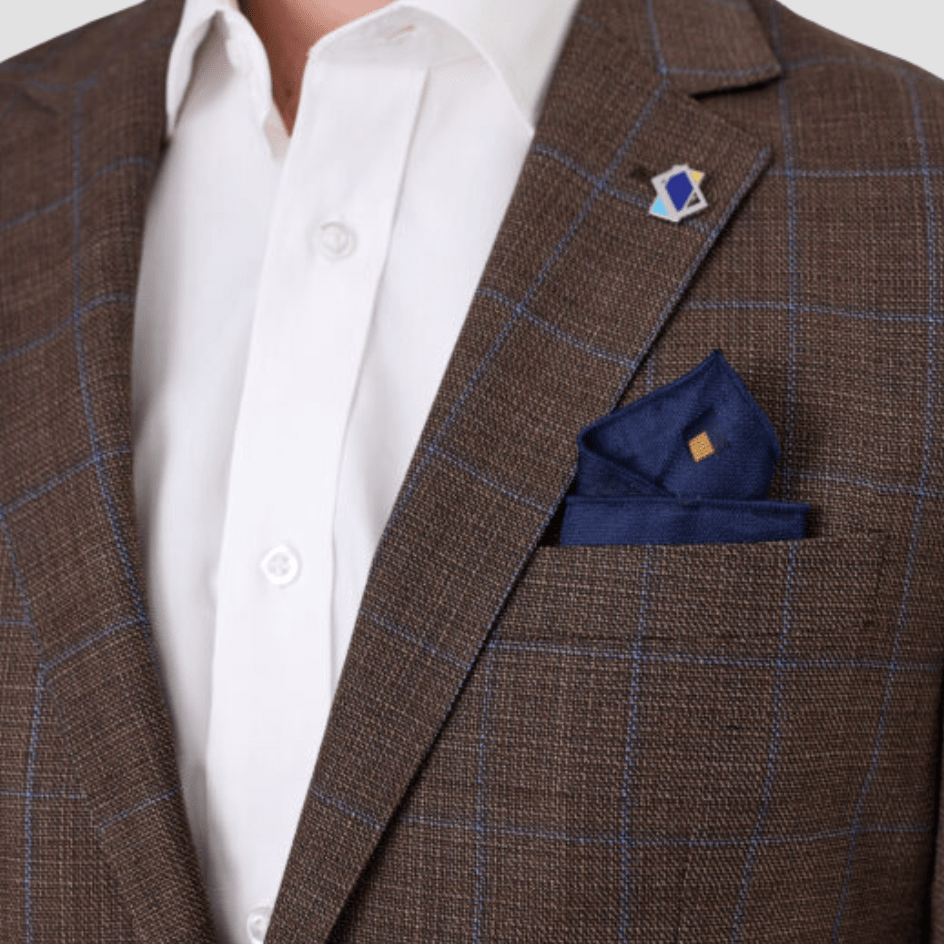 Brown checkered sports jacket by Savile Row with a blue pocket square and white shirt.
