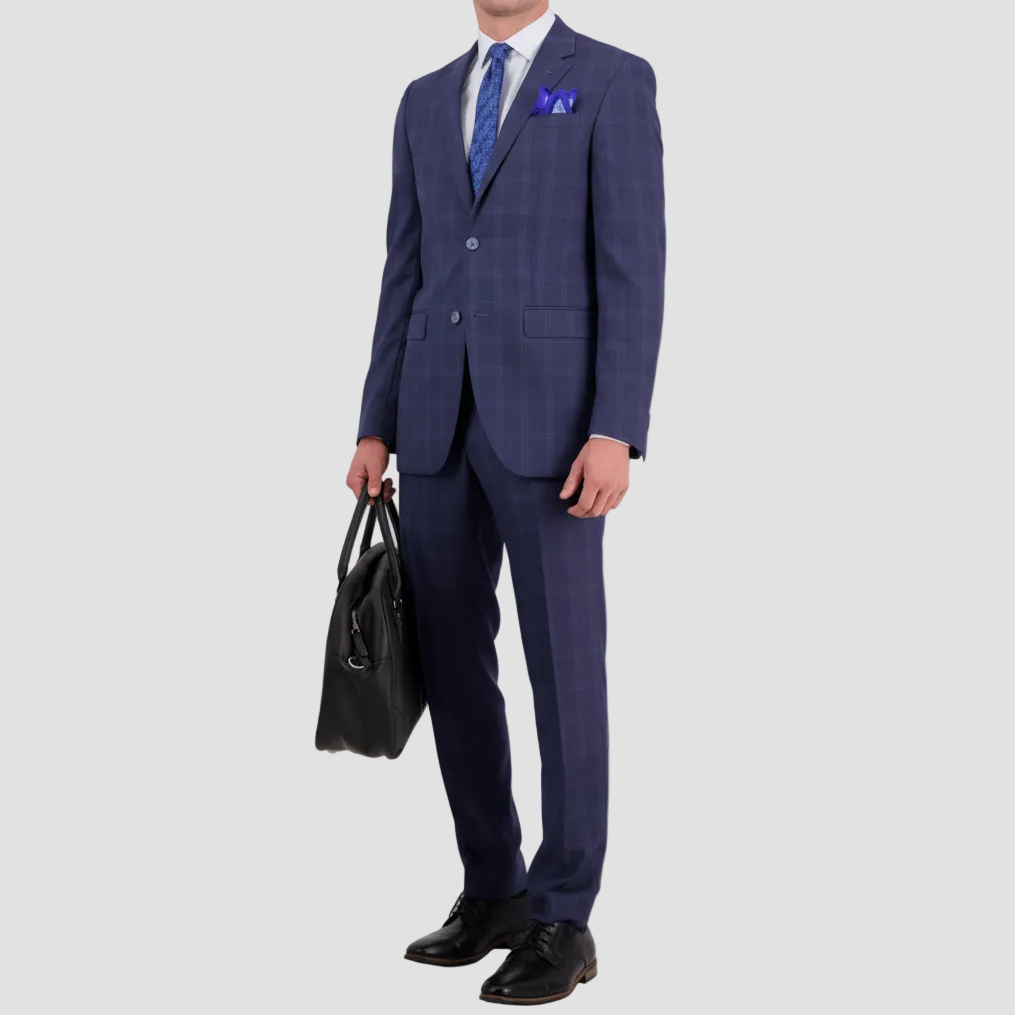 A man wearing a tailored fit cornflower blue wool cashmere suit by Savile Row, with a windowpane check pattern, featuring a notch lapel, two buttons, and a double vent. Complimented with a white shirt, blue tie and pocket square.