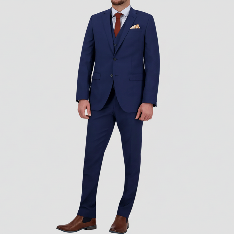 A denim blue tailored fit men's suit from Savile Row with a double button design, red tie, light shirt and brown leather shoes.