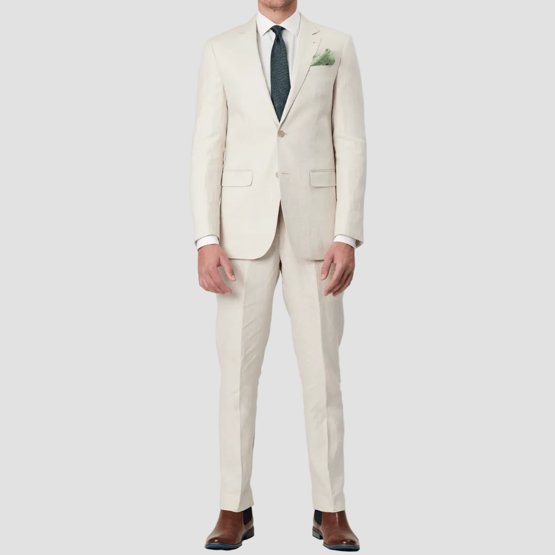 Mens pure linen ecru suit by Savile Row with a green tie and pocket square and brown leather shoes.