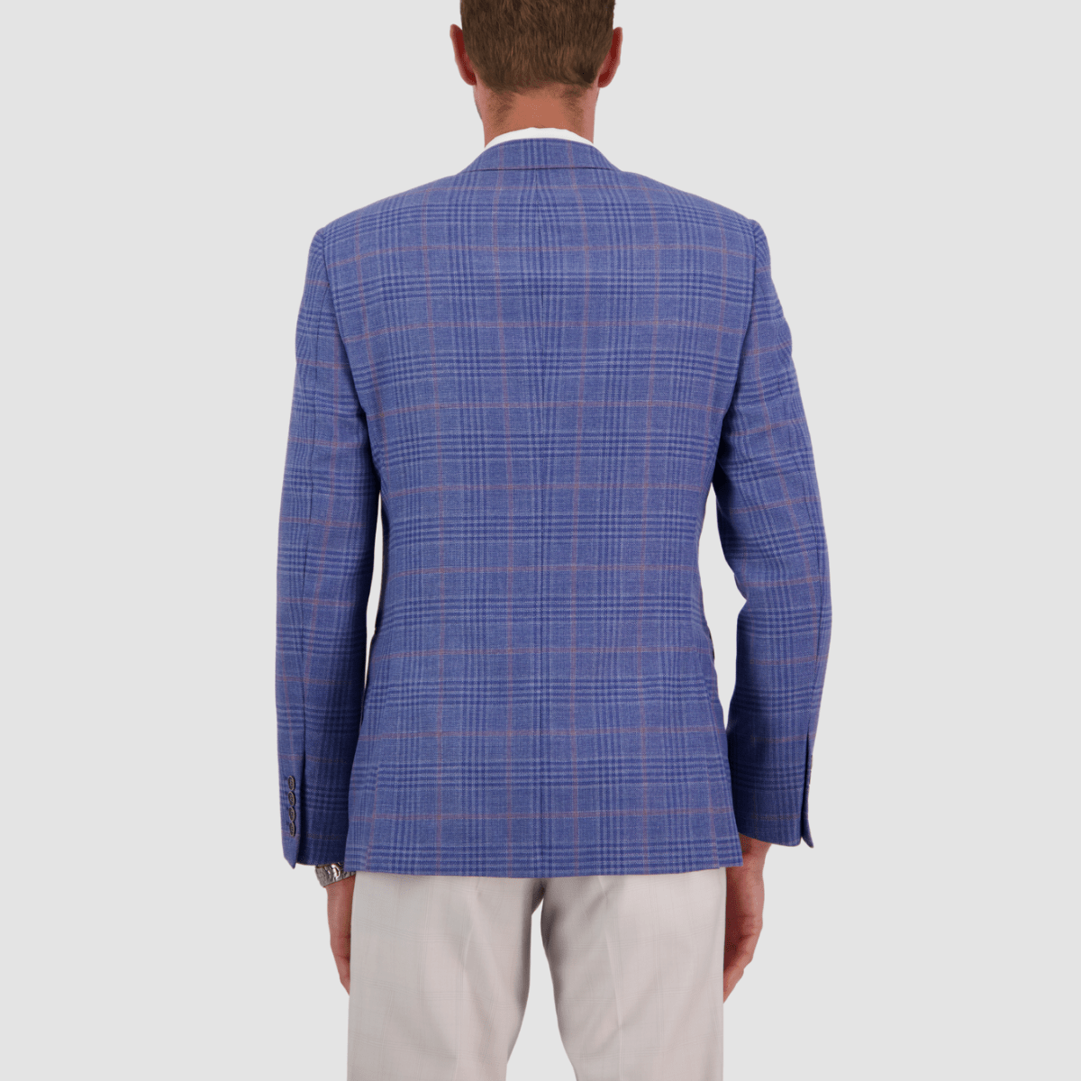 A man wearing a sky blue wool checked sports jacket with a slim fit. The jacket is paired with white trousers.