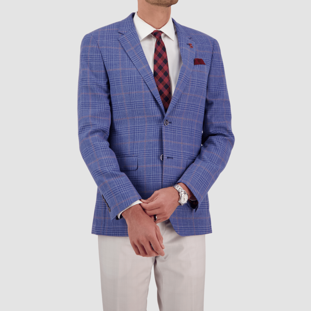 A man wearing a sky blue wool checked sports jacket with a slim fit, notch lapel, double button, and a chest pocket. The jacket is paired with white trousers.