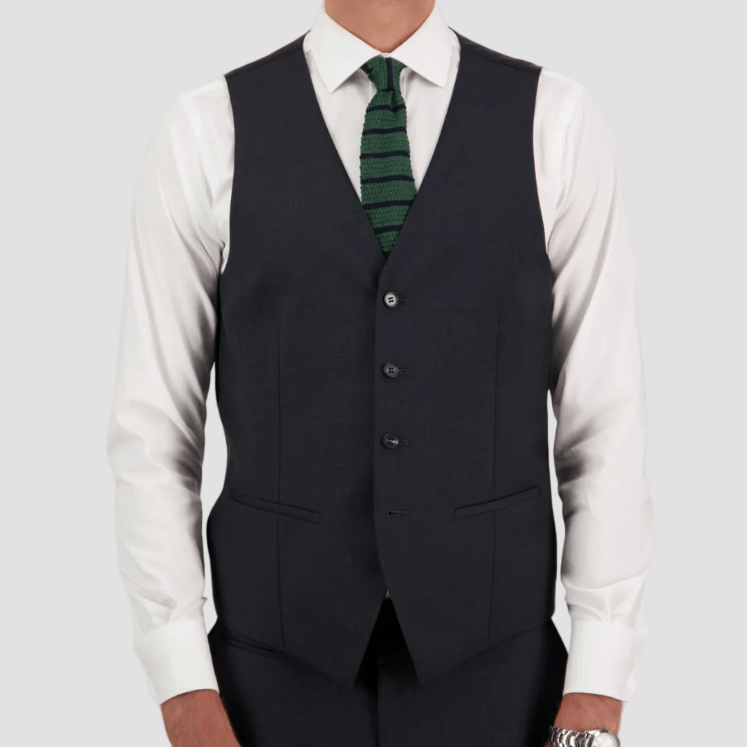 Black vest by Savile Row over a white shirt with a green tie