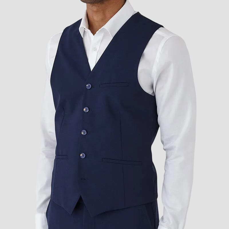 Man wearing a navy vest over a white dress shirt on a white background