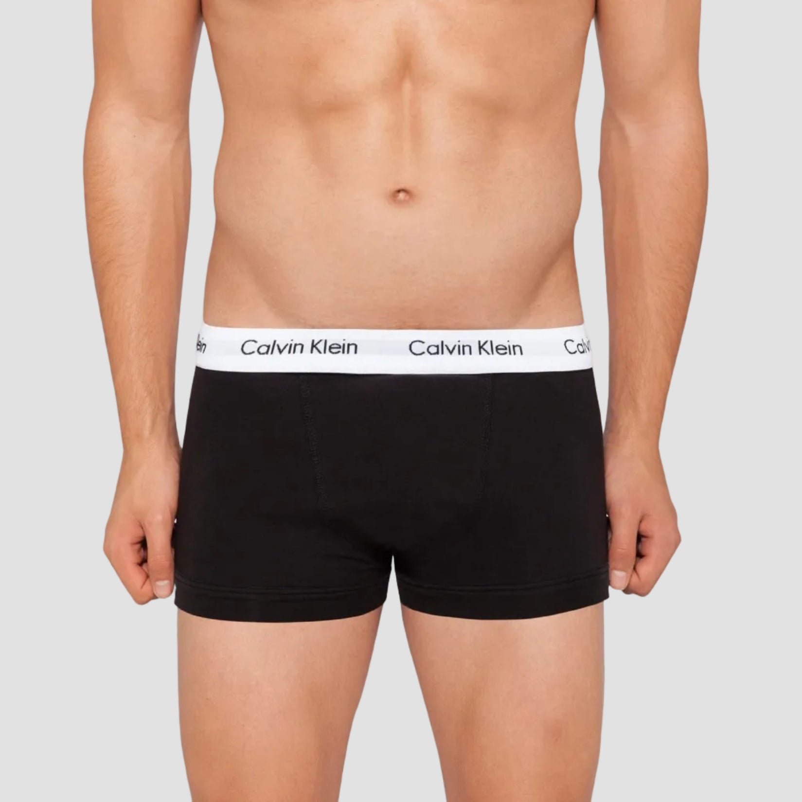 a model wears the Calvin Klein black cotton stretch trunk with a white waistband and Calvin Klein logo in black writing