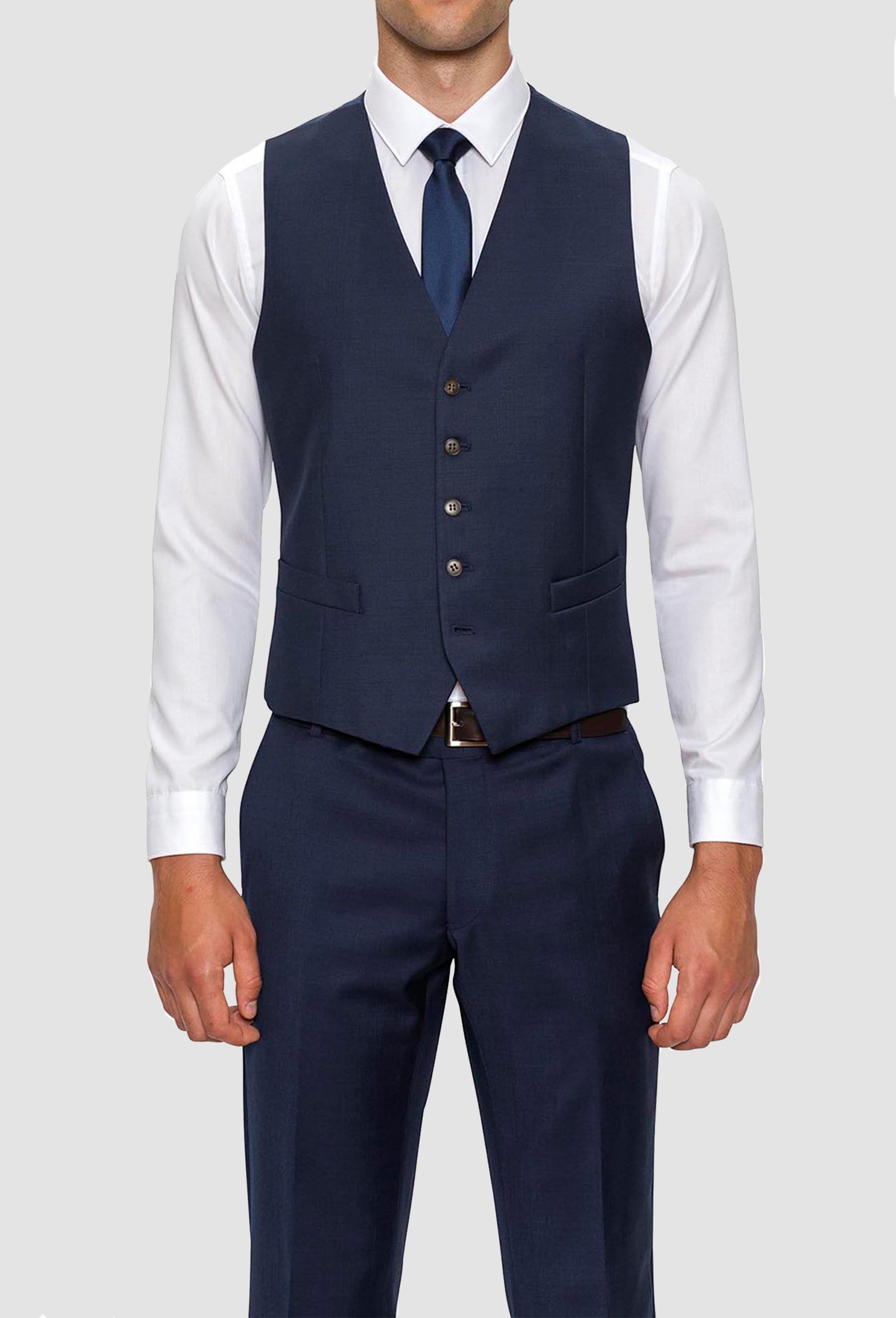 A front on view of a model wearing A model wears the Gibson slim fit mighty vest in navy pure wool with a white shirt and navy tie