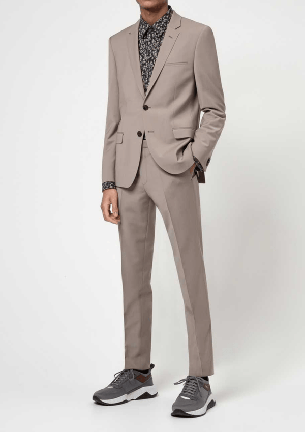  a model wears the Hugo slim fit arti hesten suit in medium beige pure wool with grey sneakers and a black printed shirt