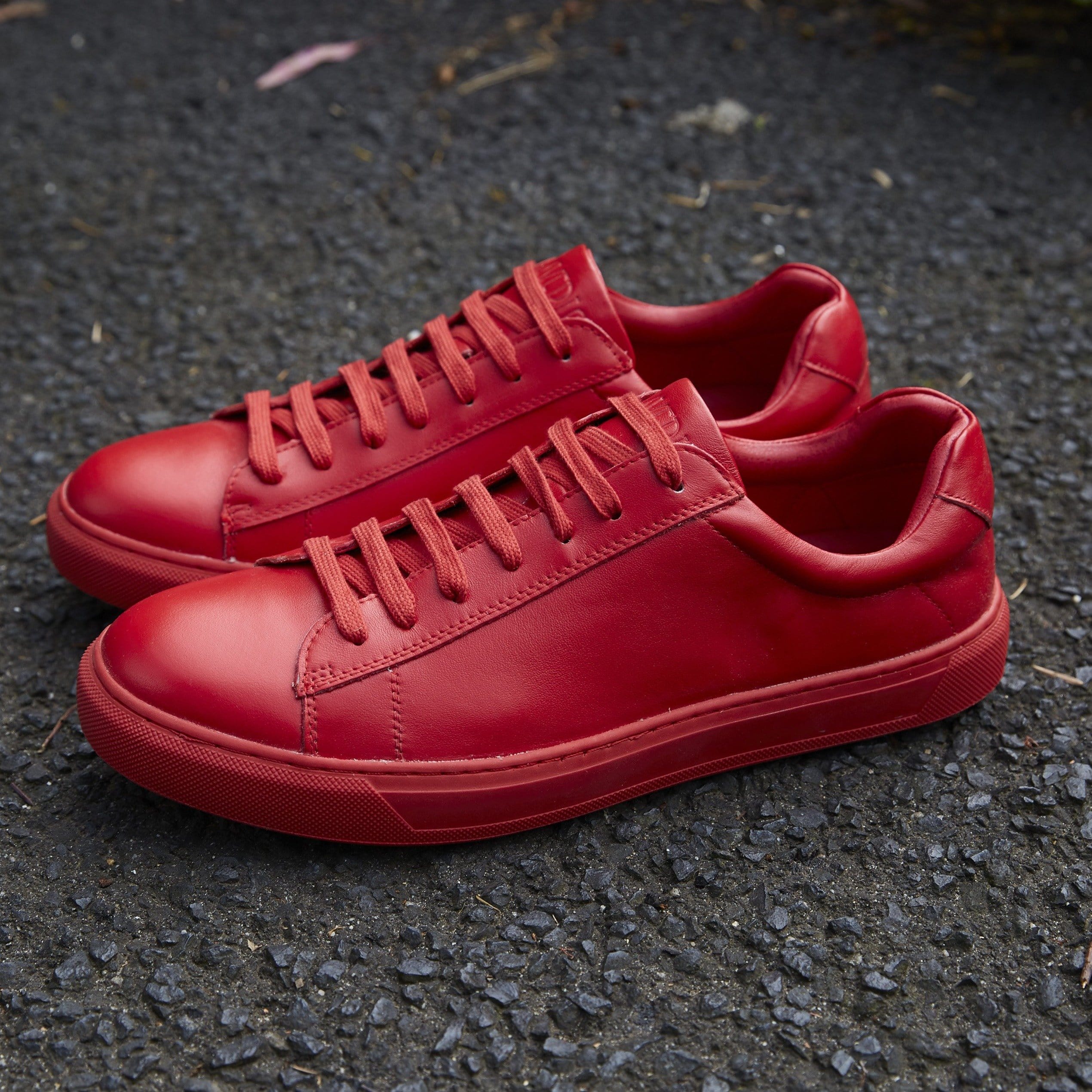 a pair of mavericks mens leather sneakers in red on the concrete