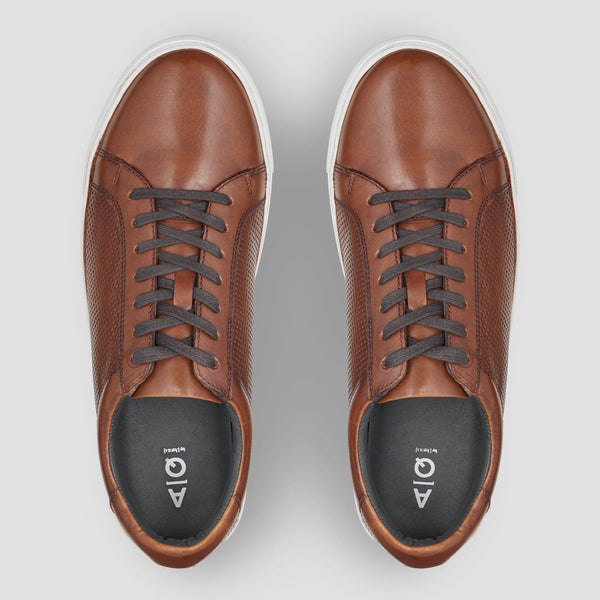 the round toe and dark brown laces of the aquila smith mens leather sneaker in tan