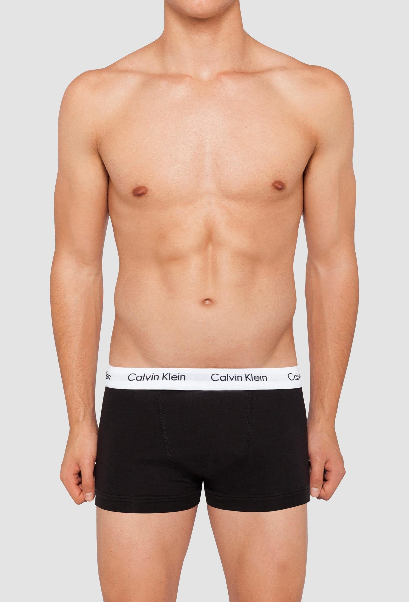 a model wears the Calvin Klein black cotton stretch trunk with a white waistband and Calvin Klein logo in black writing