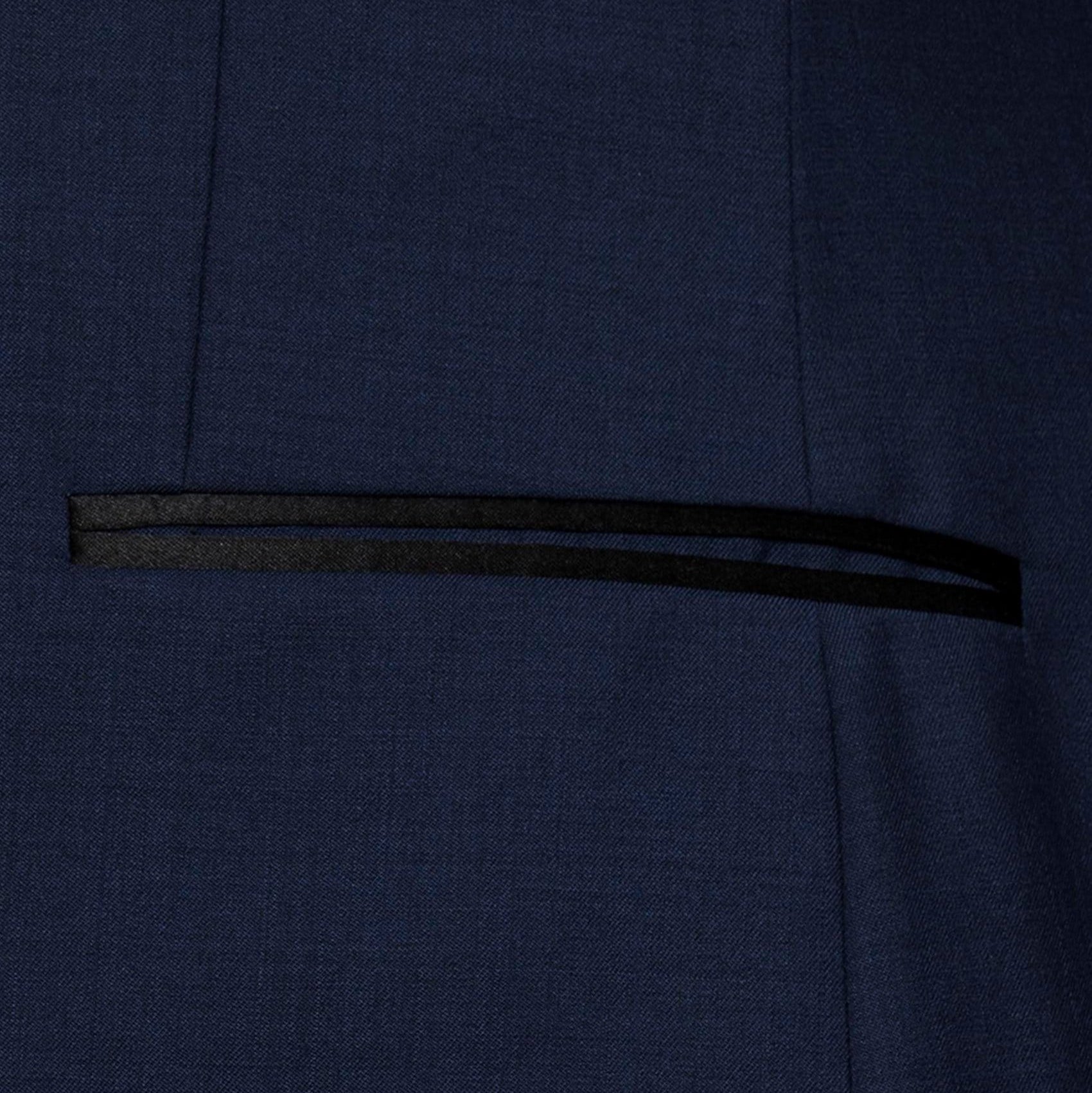 Gibson’s Spectre navy tuxedo blends a satin shawl lapel, jet pockets and 2‑button front with slim trousers.