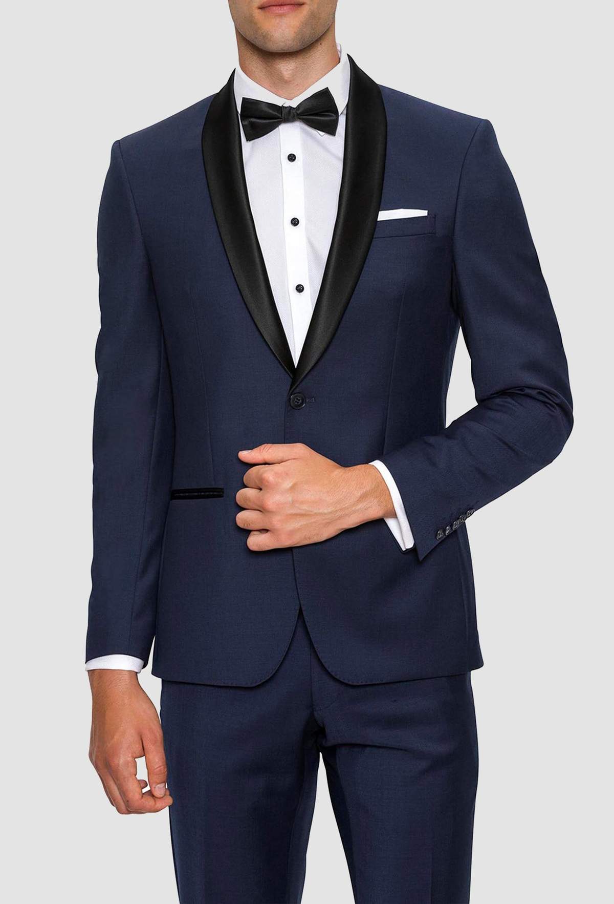 a model wears a dark navy blue tuxedo with contrasting black satin lapel with a white evening shirt underneath and a black bowtie