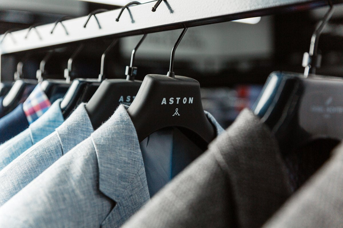 a collection of mens wool suits hanging on a rail at mens suit warehouse in Melbourne
