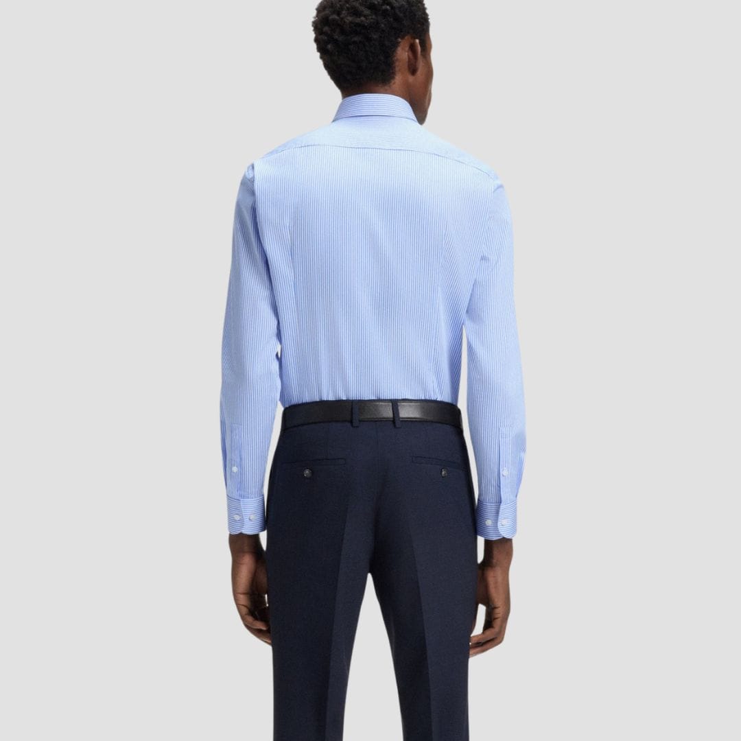 Man wearing a light blue striped dress shirt and dark blue pants 