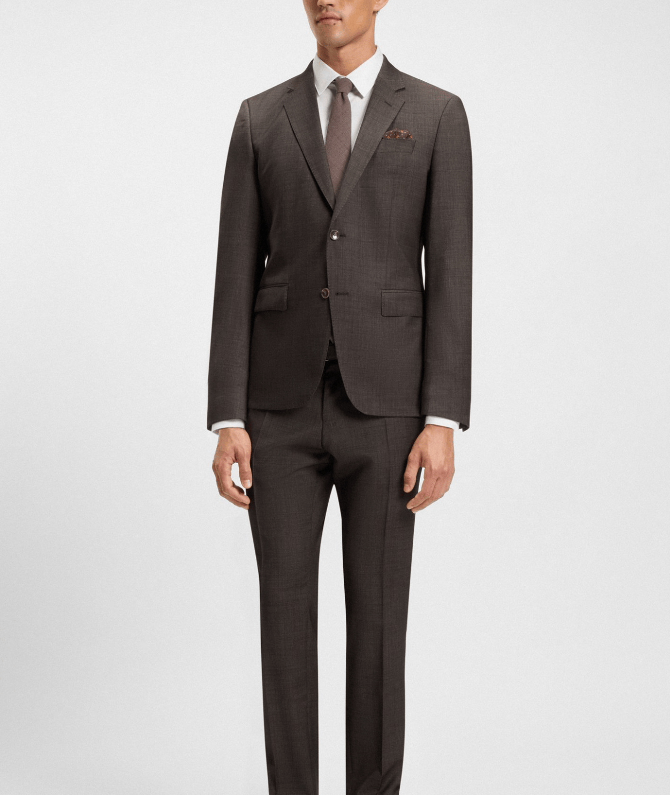 Man wearing a brown suit with a white shirt and tie on a light gray background