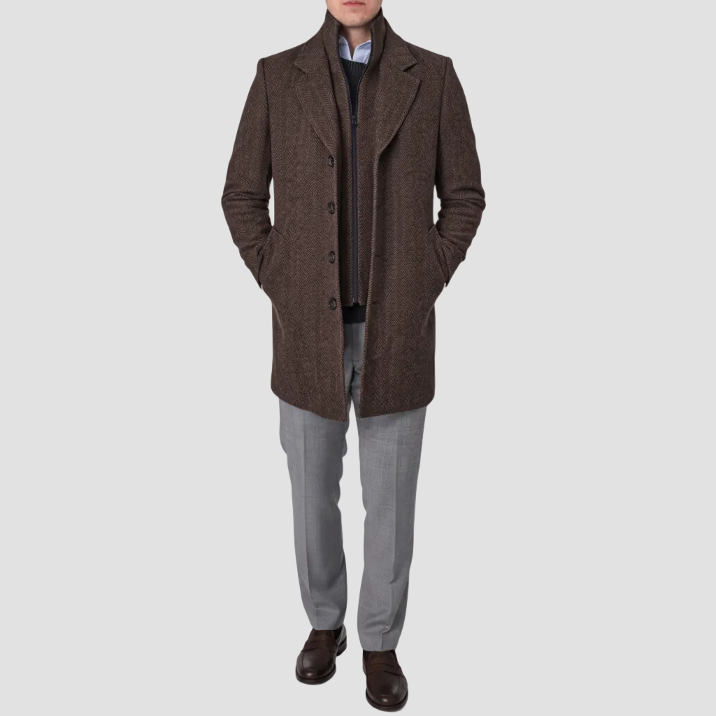 A man wearing a brown coat with a removable collar, buttoned sleeves, and an inner zip fastening.