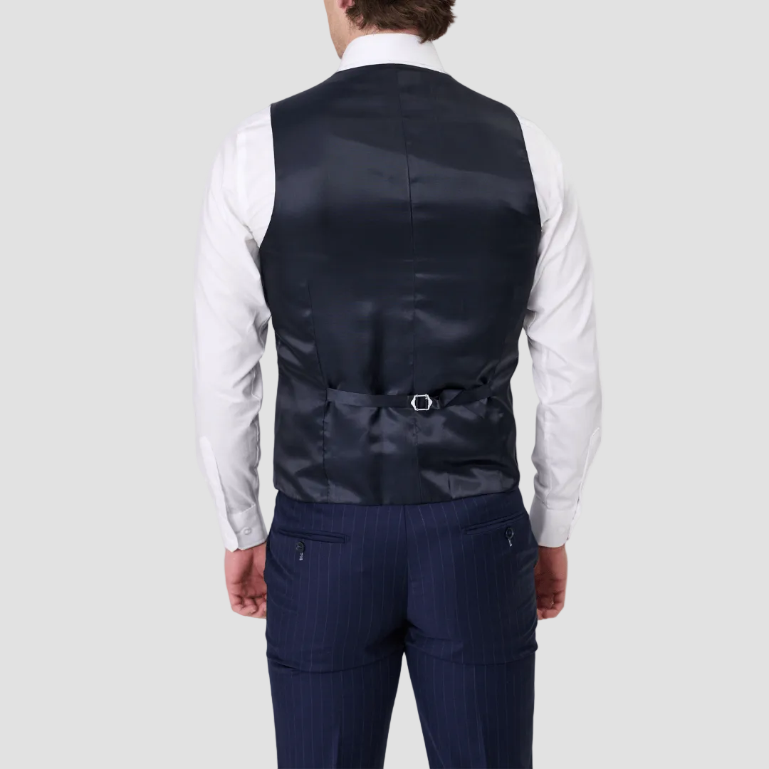 Man wearing a navy pinstripe suit vest by Savile Row, with a satin back, adjustable tab, and paired with a white shirt.