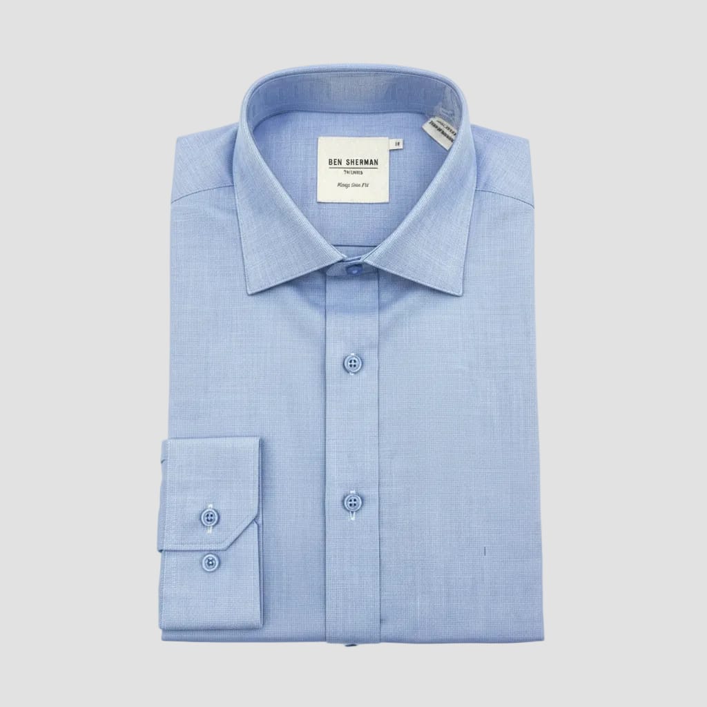 Blue dress shirt with a tag held by a hand on a dark surface