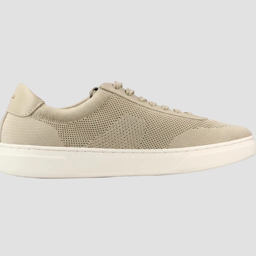 A low-top knit sneaker in a light beige or sand color with a thick white sole, shown from a side profile view against a white background.