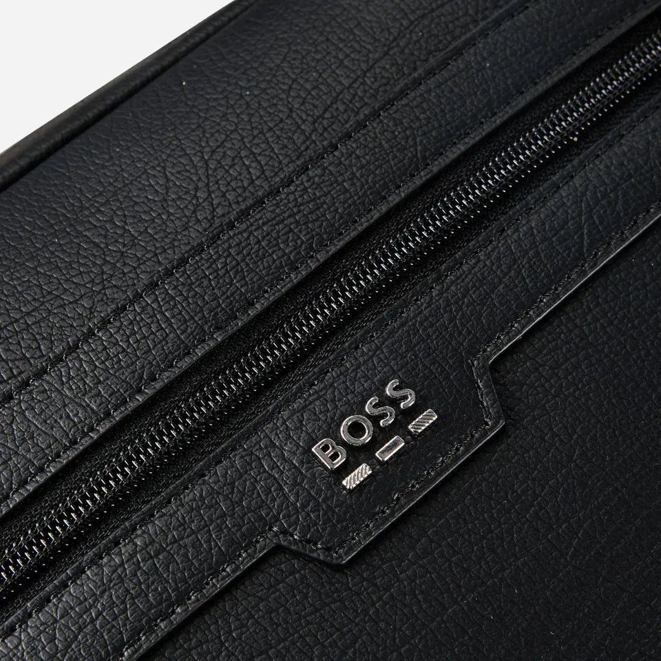 Close-up of a black textured leather bag with a diagonal zipper and a silver-tone BOSS logo plaque on a black leather tab.