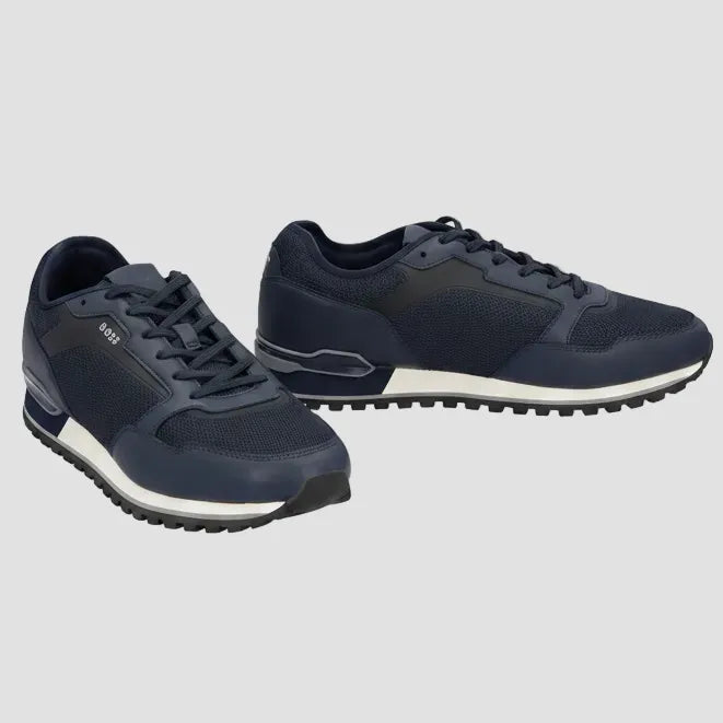 A pair of navy blue low-top sneakers with dark gray panels, navy laces, and a white midsole, shown against a plain white background.
