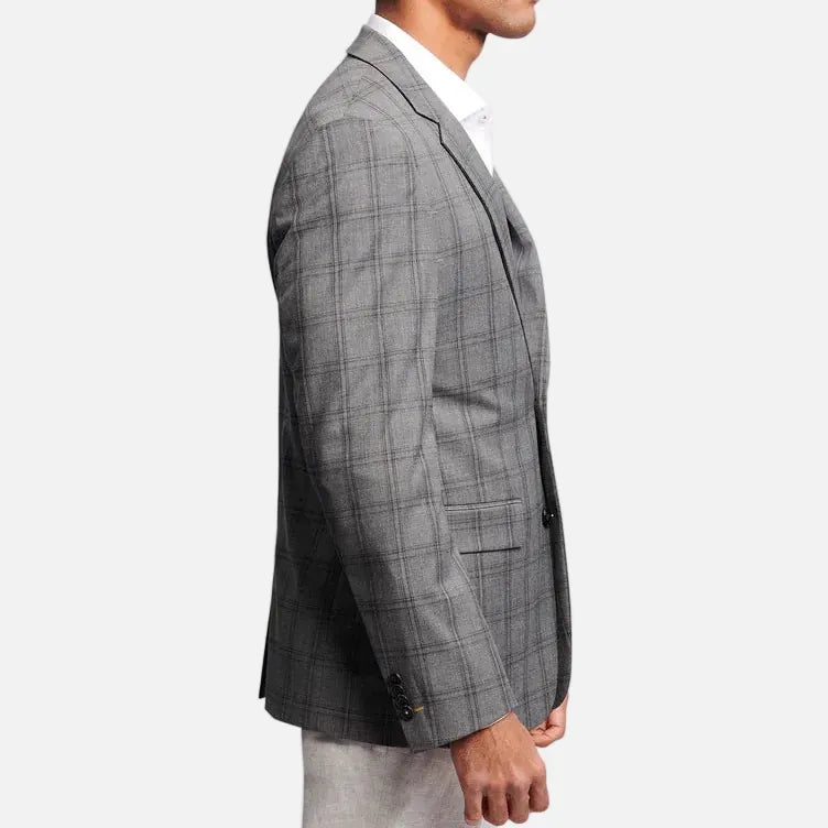 A man shown in profile wearing a gray plaid blazer over a white collared shirt, photographed against a plain light gray studio background.
