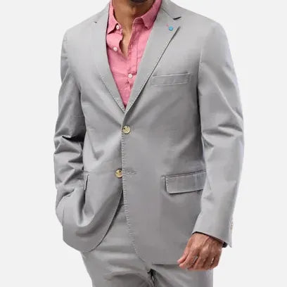 A man modeling a light gray two-piece suit with a pink button-down shirt and brown loafers, standing against a solid light gray background.