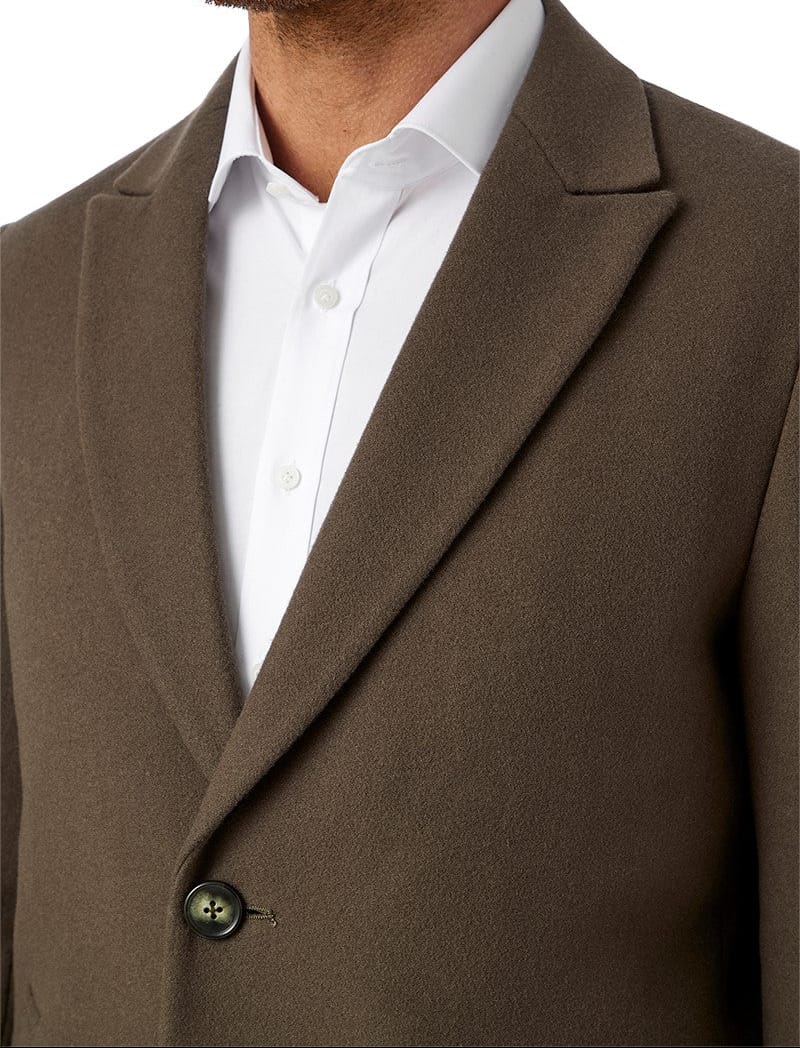 Brown coat worn by a person with a white shirt underneath, on a plain background