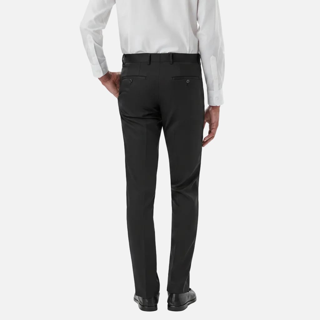 Rear view of a person wearing black dress pants with a white dress shirt and black dress shoes, shown against a plain white studio background.