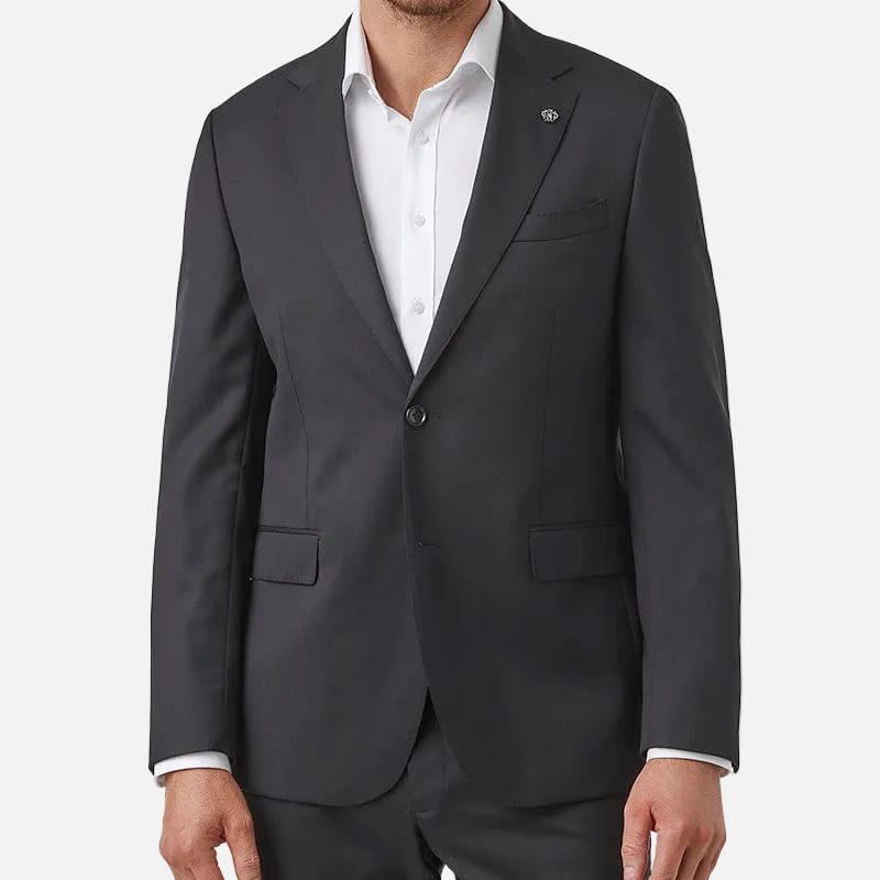 A man wearing a black two-piece suit with a white dress shirt, standing against a solid white background.